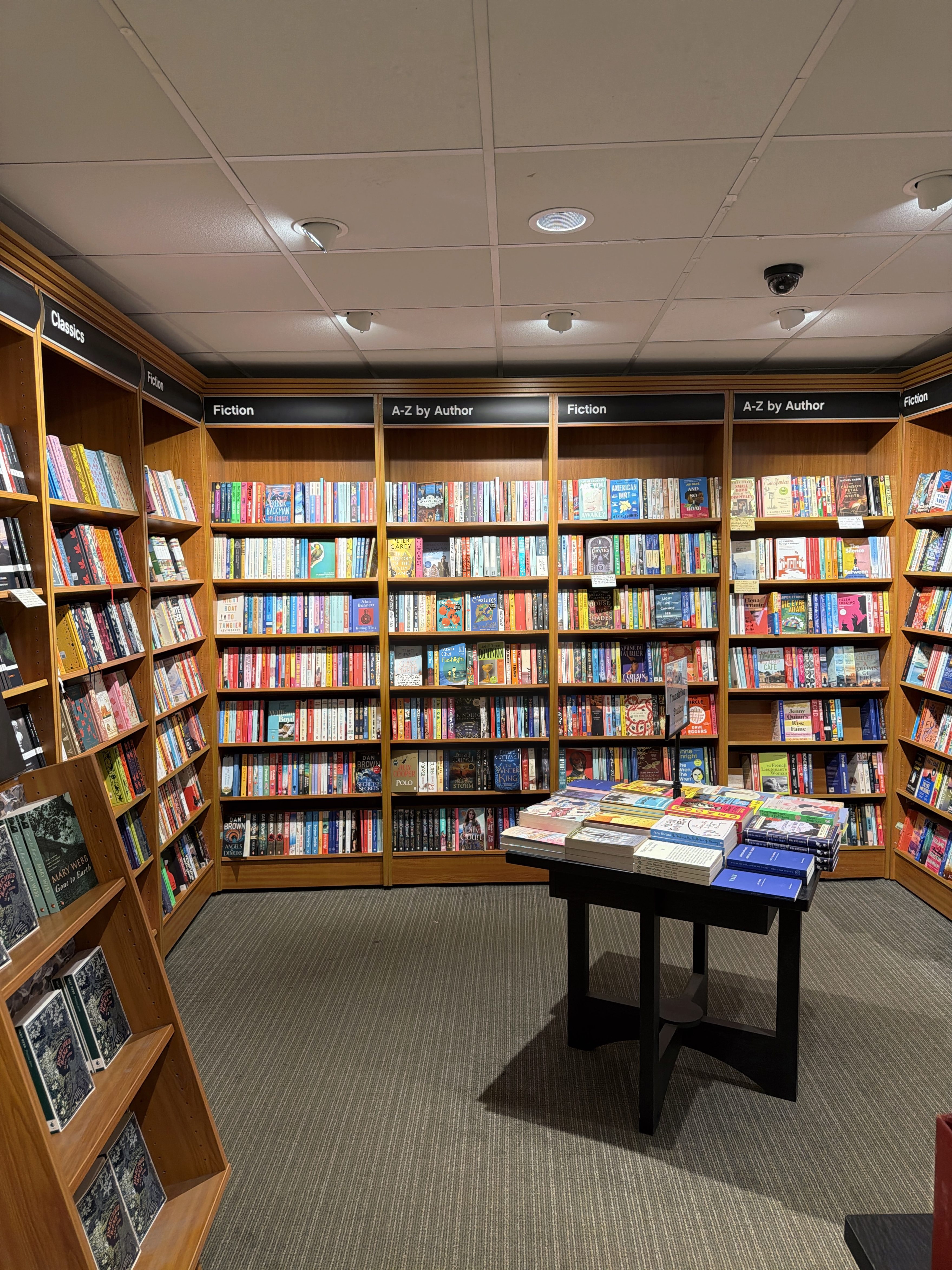 A bookshop shelf across the room, photographed with Photosynthesis: every book spine is readable.